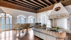 A spacious living room with a grand piano, a large beige sofa, and a fireplace. - Lake Front Villa Schlosser (Malcesine)