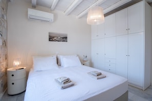 A bedroom with a large bed, white wardrobe, and a nightstand with a lamp.