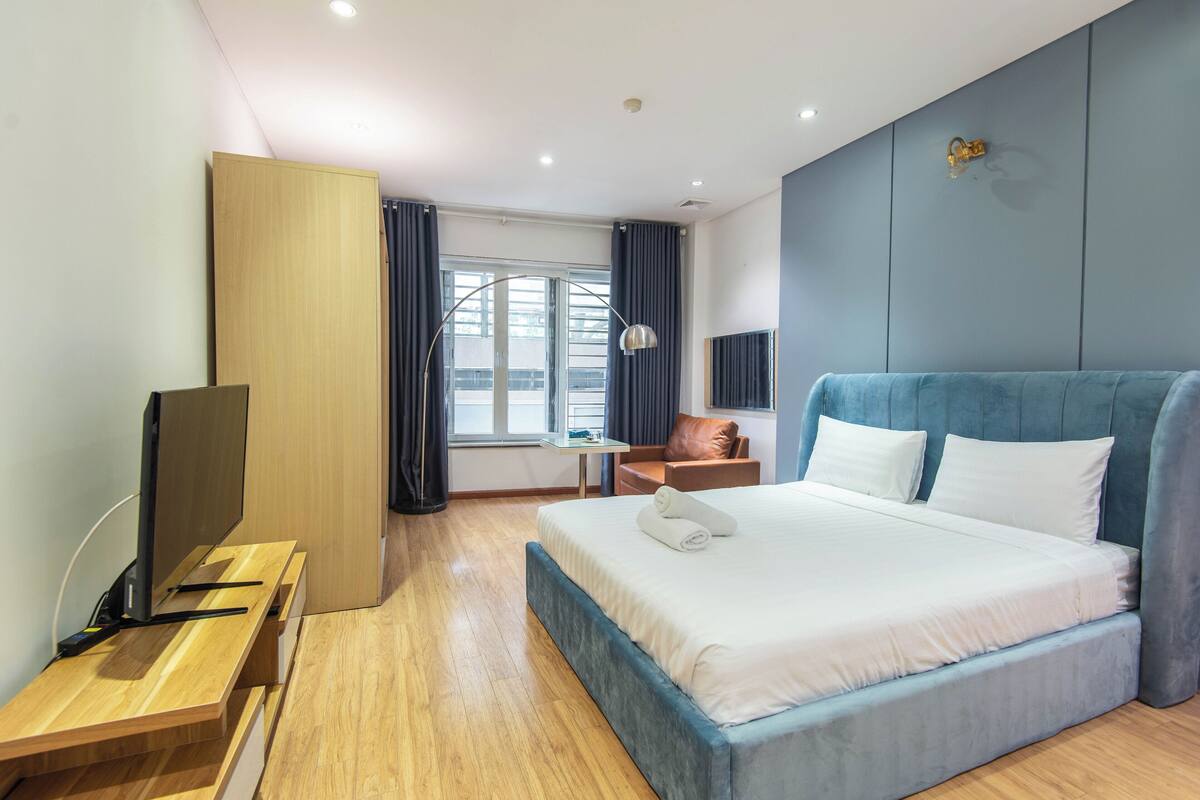 Una habitación de hotel moderna con una cama grande, un escritorio, una silla y un televisor.