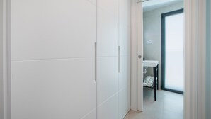 Un couloir menant à une salle de bain avec une porte blanche, un lavabo et des serviettes.