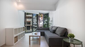 Un salon moderne avec un canapé gris, une petite table et une plante en pot.