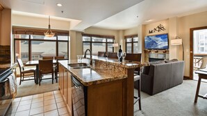 Una cocina amplia con una isla grande, comedor y una sala de estar acogedora con sofá y televisor.