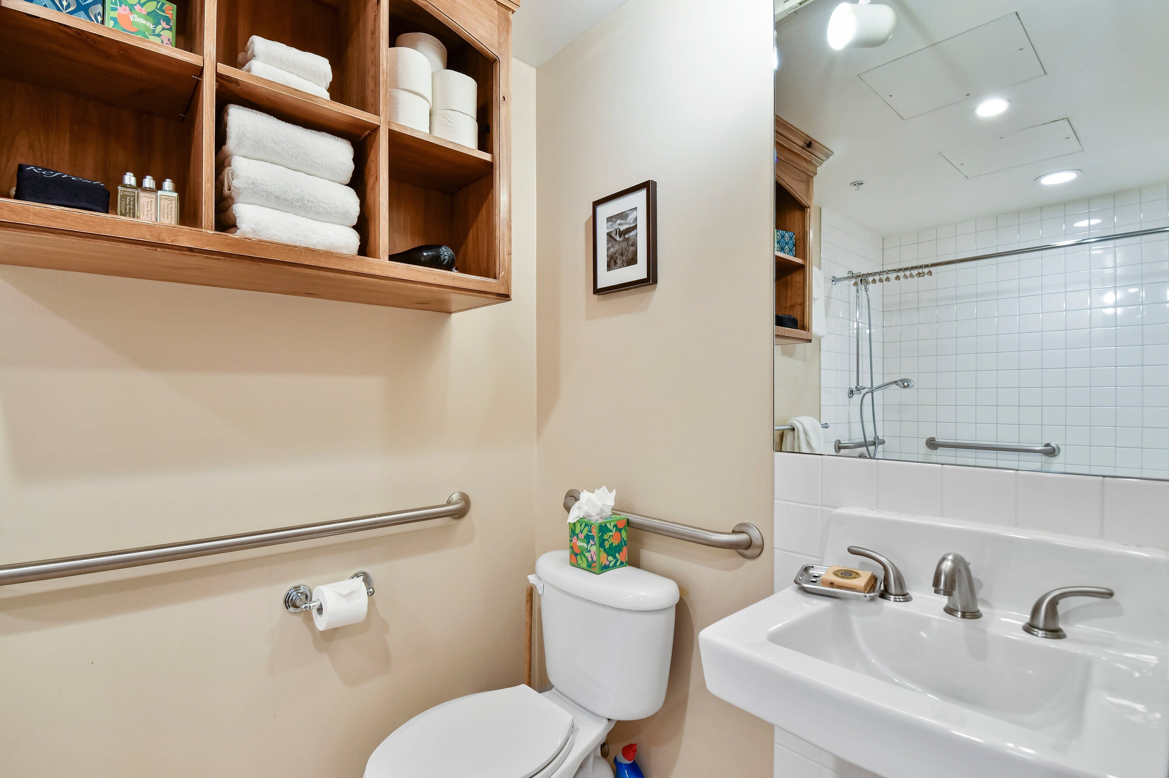 Une salle de bain équipée de toilettes, d’un lavabo et d’étagères où sont rangées les serviettes et les articles de toilette.