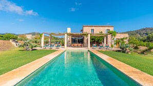 A pool with a stone house in the background.