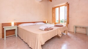 Une chambre avec un grand lit, des tables de chevet et une fenêtre avec des volets en bois.