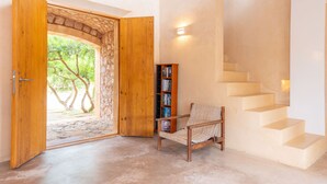 Une pièce dotée d’une arche en pierre menant à un espace extérieur, d’une chaise en bois, d’une bibliothèque et d’un escalier.