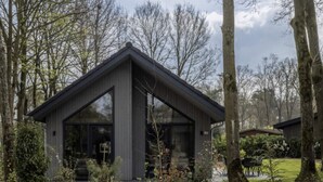 A modern building with a sloped roof, surrounded by trees and a well-maintained lawn. - Eco Villa Near Forest in Netherlands (Oirschot)