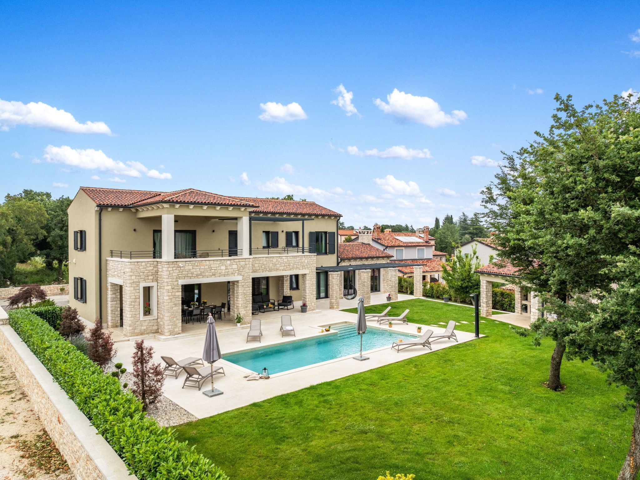 Uma casa de dois andares com piscina, área de estar externa e gramado bem cuidado.