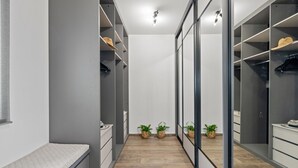 Een moderne inloopkast met grijze wanden, houten vloeren en ingebouwde planken.