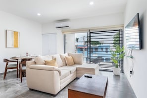 A modern living room with a sofa, coffee table, dining table, and chairs.