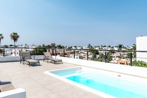 A rooftop pool area with lounge chairs and a clear view of the cityscape.