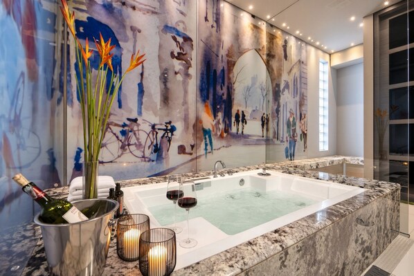 Ein modernes Badezimmer mit einer großen Badewanne, einer Glasabtrennung und einem Wandbild.