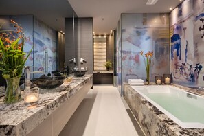 Une salle de bain moderne avec un grand miroir, une baignoire et un comptoir en marbre.