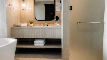 Un baño moderno con un espejo grande, una bañera y un tocador con perchero.