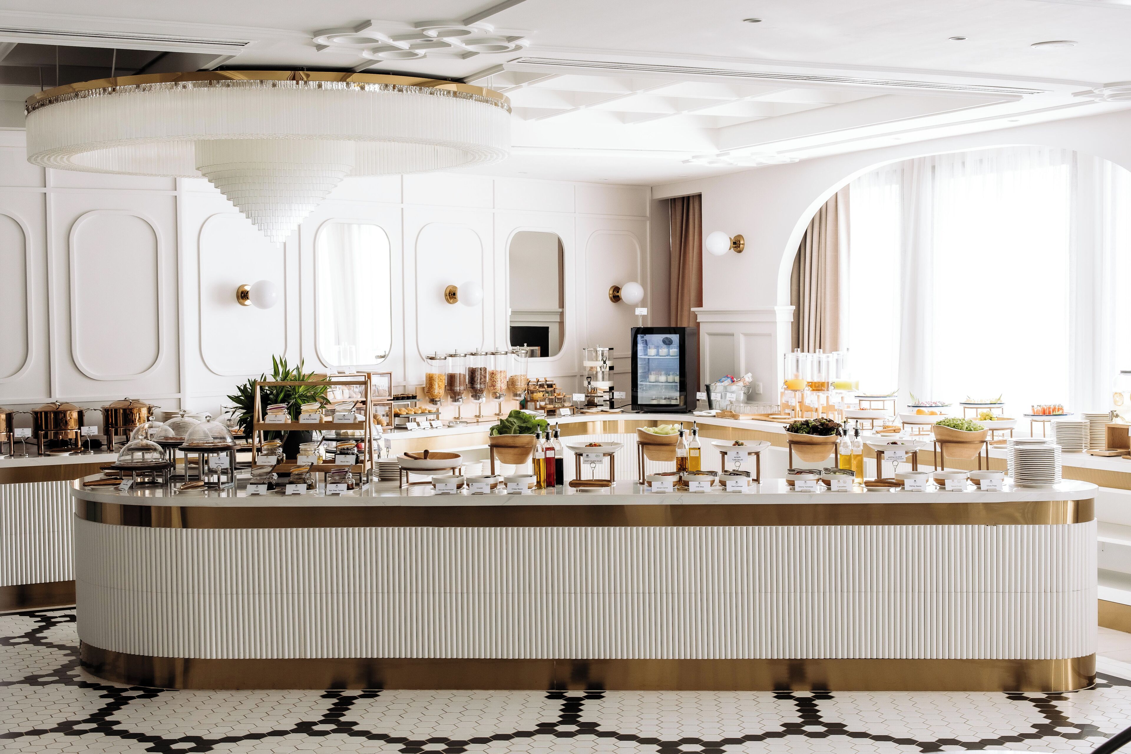 A luxurious hotel lobby with a central reception desk, large windows, and elegant decor.