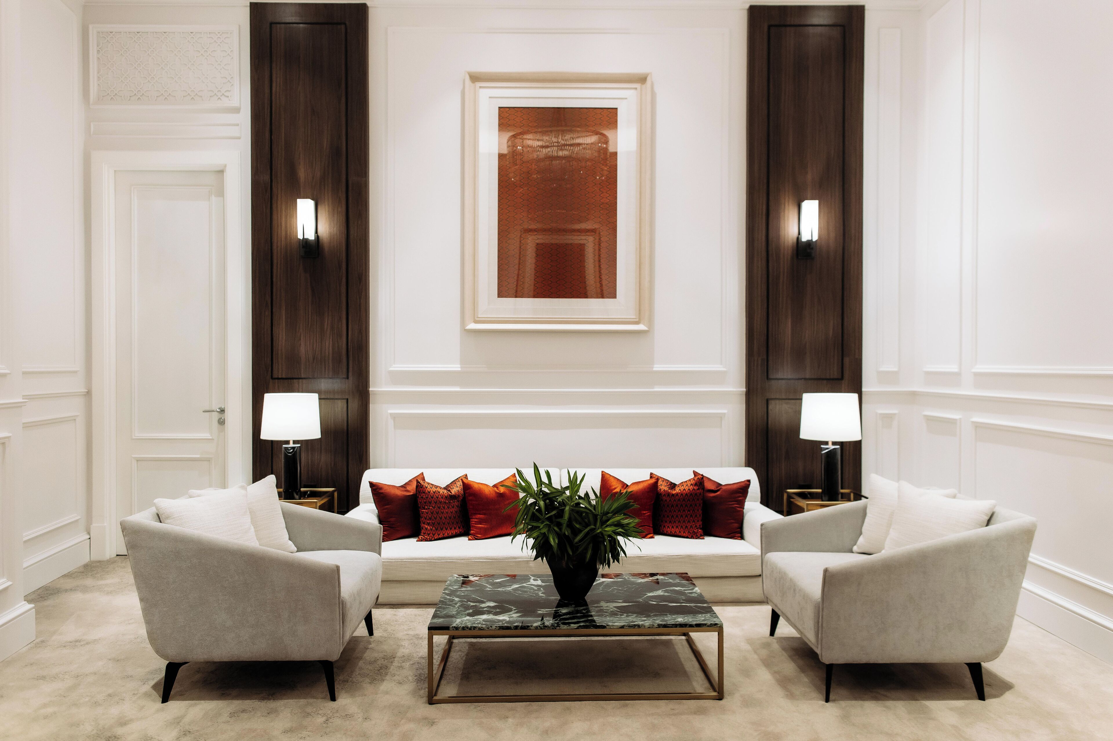 Un salon moderne comprenant un canapé, deux fauteuils, une table basse et une plante décorative.