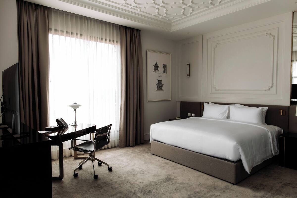 Hotelkamer met een groot bed, een bureau met stoel, een flatscreen-tv en een lamp.