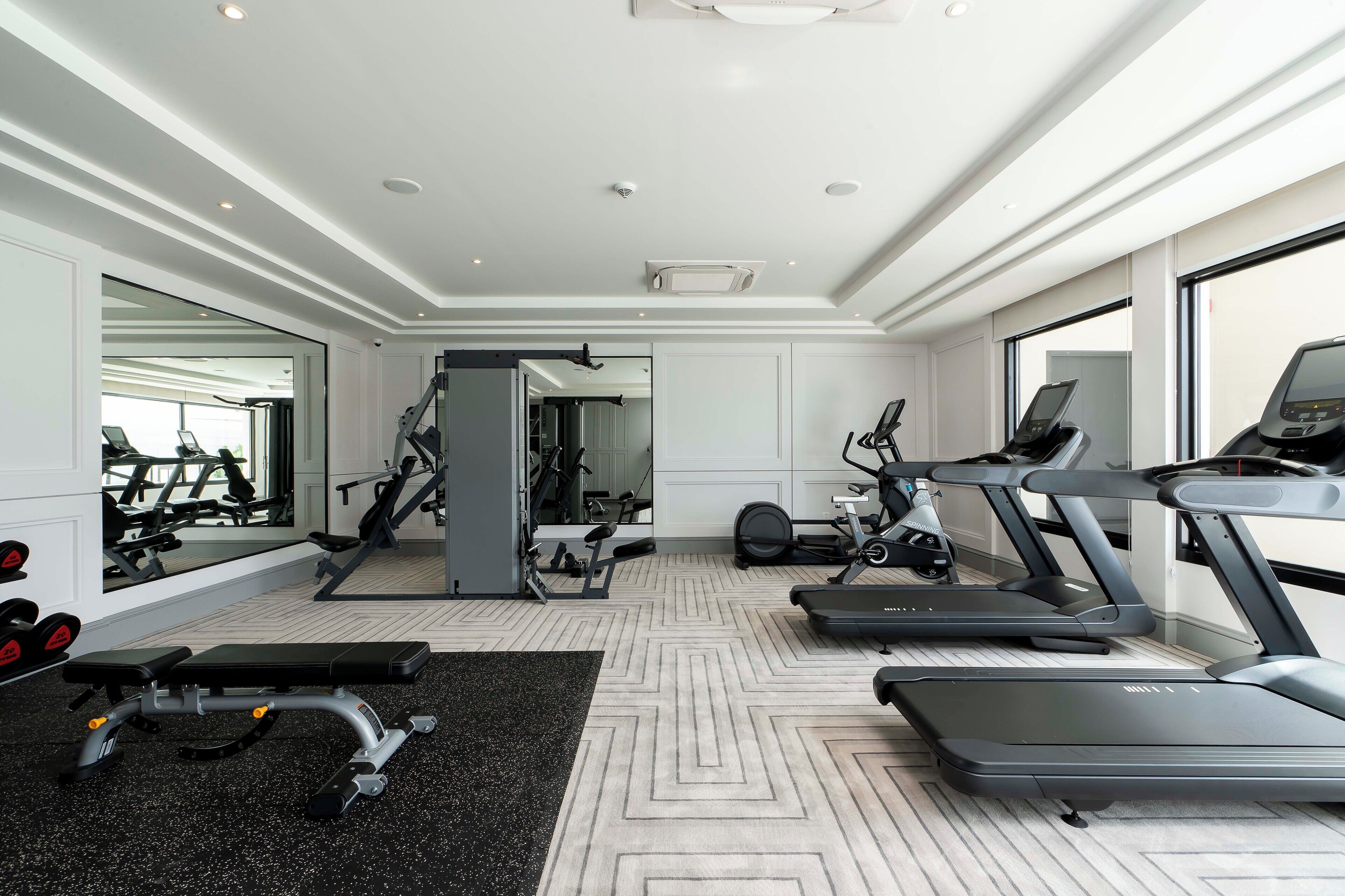A modern gym with treadmills, a bench, and weight machines.