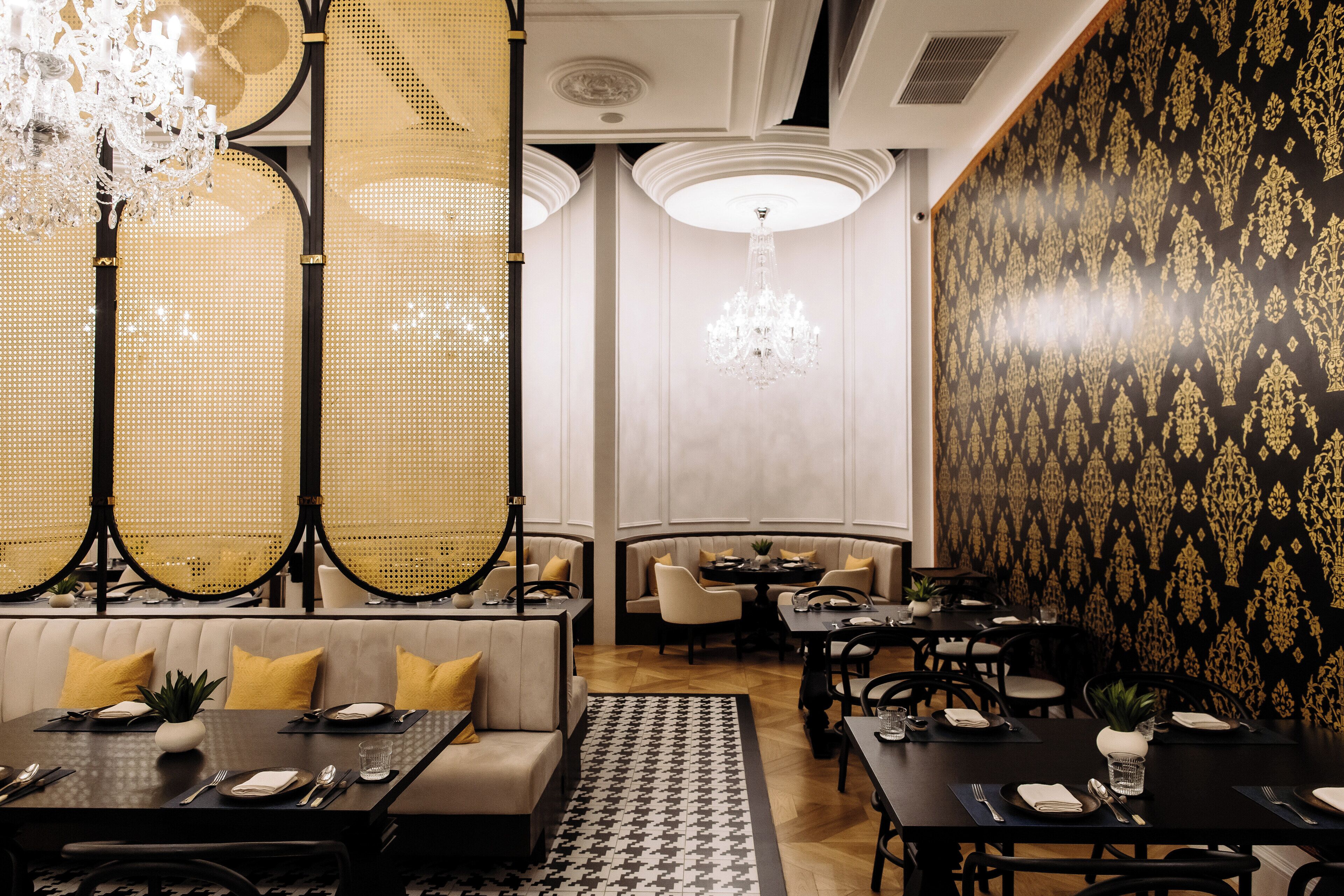 Un comedor con asientos tipo cabina y mesas, candelabros y papel tapiz estampado.