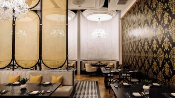 Un comedor con asientos tipo cabina y mesas, candelabros y papel tapiz estampado.