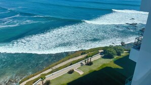 Une vue sur la côte depuis un balcon, avec un chemin dégagé menant à la plage et donnant sur l’océan.
