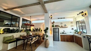 A spacious living area with a dining table, sofas, and a kitchen with a refrigerator and sink. - Arcadia Lodge (Canggu)