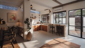 A spacious kitchen with a large island, bar stools, and a view through large windows. - Arcadia Lodge (Canggu)