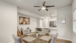 A dining area with a large table, chairs, a ceiling fan, and a kitchen in the background. - Sakura Springs (Colorado Springs)