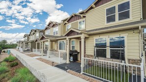 A row of townhouses with a covered patio area, a barbecue grill, and a stone facade. - Sakura Springs (Colorado Springs)