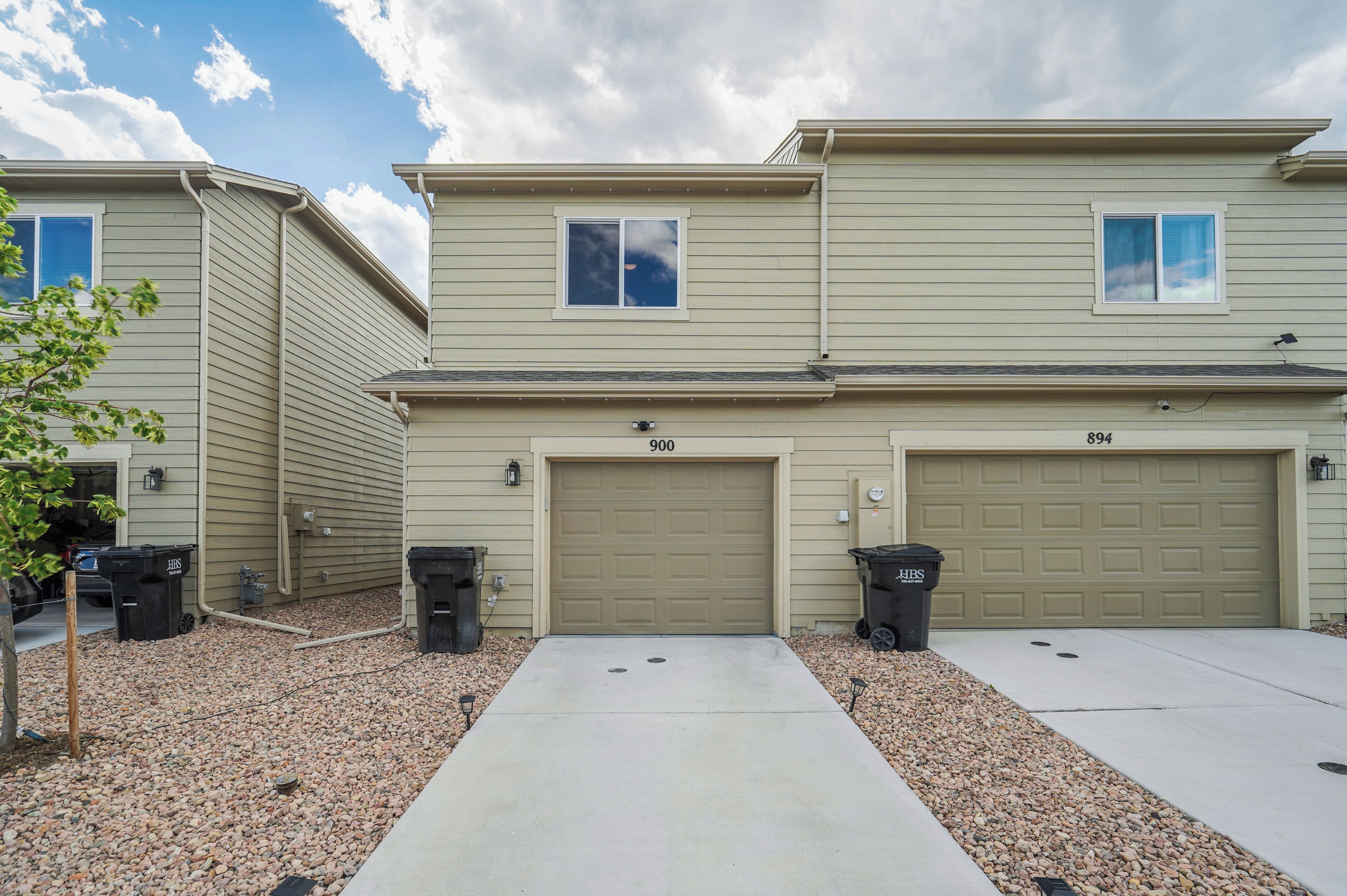 A two-story residential building with numbered garage doors 900 and 894.