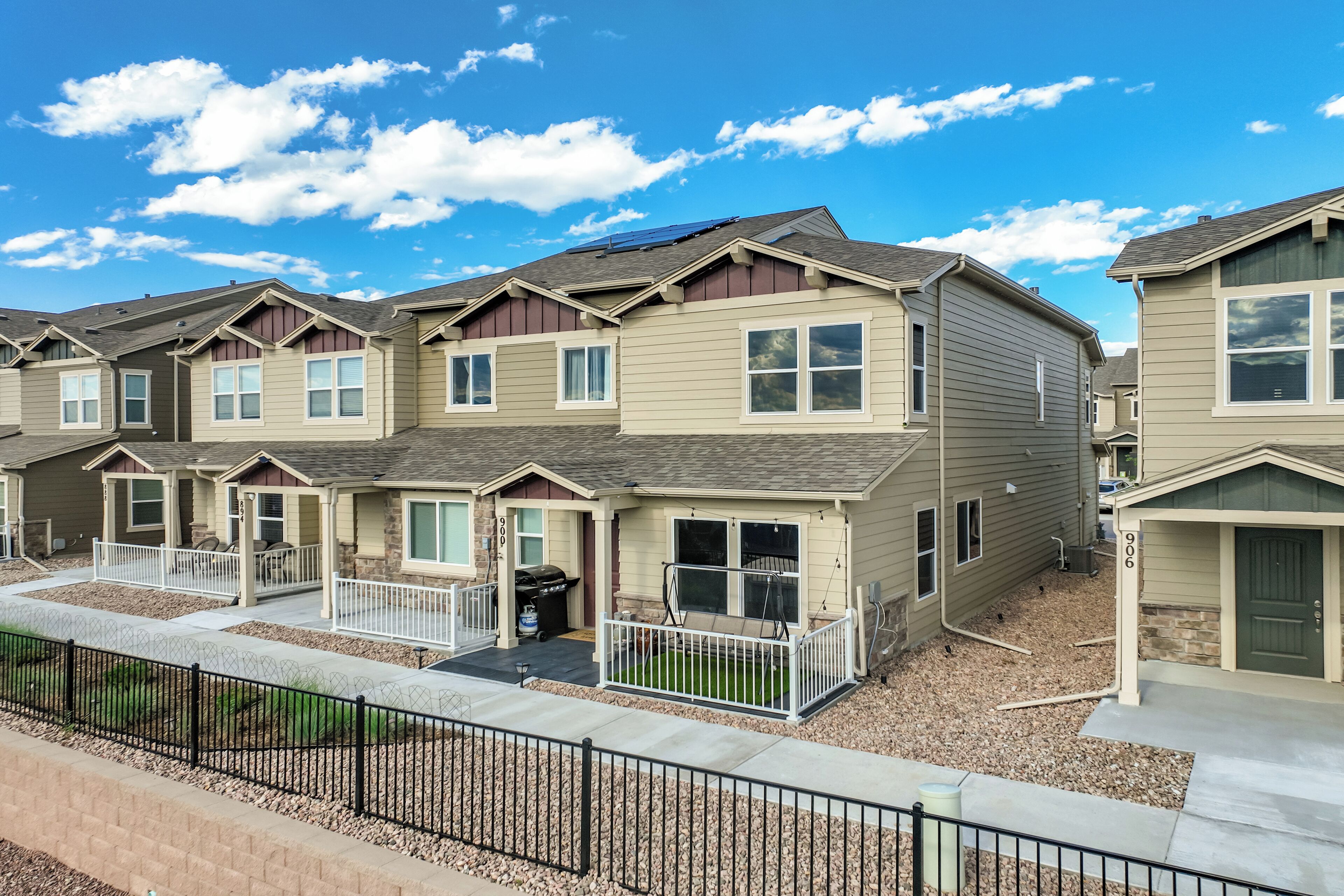 A row of townhouses with a common entrance, a small patio, and a solar panel on the roof.