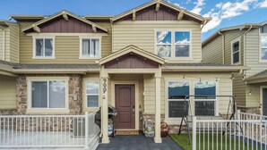 A two-story house with a front porch, stone foundation, and a brown door. - Sakura Springs (Colorado Springs)