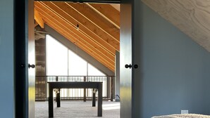 Un interior moderno con un ventanal grande, techo de madera y vistas a un espacio exterior.