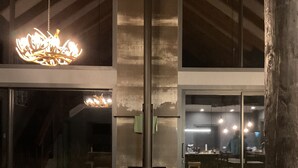 Una sala de estar moderna con una chimenea grande, sofás grises y una araña.