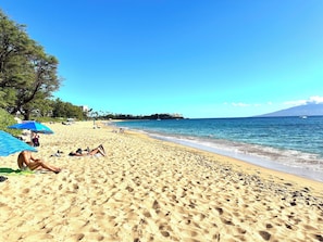 A beach with people sunbathing, umbrellas, and a clear view of the ocean. - Newly Remodelled 4-bedroom cottage in Amazing Kaanapili with ACs (Lahaina)