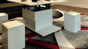Un salon moderne avec un canapé blanc, une table basse et un écran de projection diffusant un film.