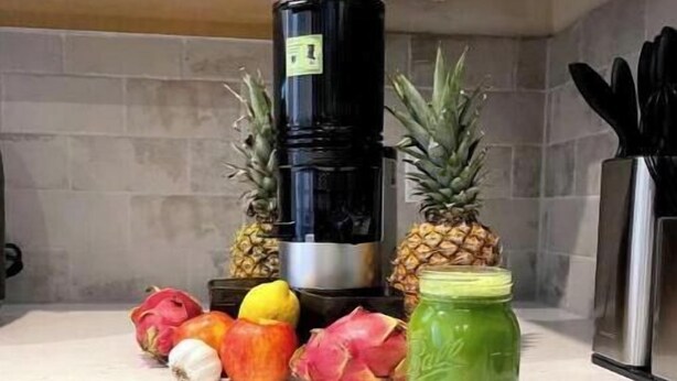 Un plan de travail de cuisine avec un mixeur, des fruits et un bocal contenant un smoothie vert.