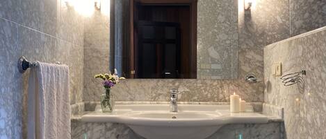 A bathroom with a marble sink, a mirror above it, and a towel hanging on the wall.