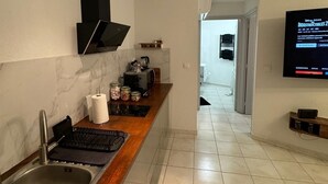 Eine moderne Küche mit Einbauherd, Spüle und einem an der Wand befestigten Flachbildfernseher.