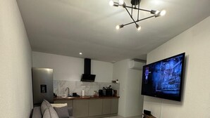 Ein modernes Wohnzimmer mit einem grauen Sofa, einem Couchtisch und einem an der Wand befestigten Fernseher.