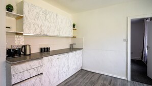 Una cocina compacta con armarios de mármol, una encimera y un suelo de madera gris.