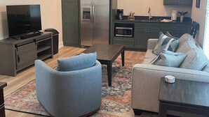 Een moderne woonkamer met een televisie, twee banken, een salontafel en een plafondventilator.