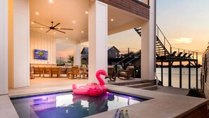 Ein Swimmingpool mit einem rosa Flamingo-Schwimmpflegegerät, einem Deckenventilator und Blick aufs Meer.