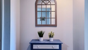 A wall-mounted mirror with a wooden frame and a blue dresser below it.