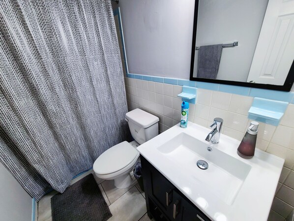 Un baño con inodoro, lavamanos y cortina de ducha.