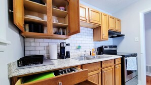 A kitchen with wooden cabinets, a stainless steel sink, a coffee maker, and an oven.
