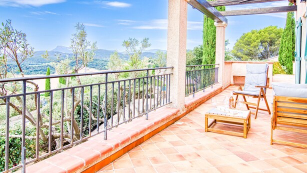 Ein Balkon mit Blick auf eine Berglandschaft, einem Holztisch und zwei Stühlen.