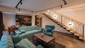 Un salon moderne avec un canapé d’angle, une table basse et un escalier doté d’une rampe aux motifs géométriques.