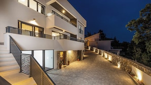 Un bâtiment moderne à plusieurs étages, doté d’un escalier, d’un mur en pierre et d’un éclairage extérieur.