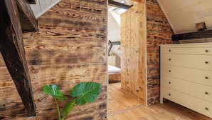A wooden interior with a bed, a dresser, and a large plant. - Mimi Cottage w/ Sauna near Kolpa River, Gradac, Slovenia (Gradac)